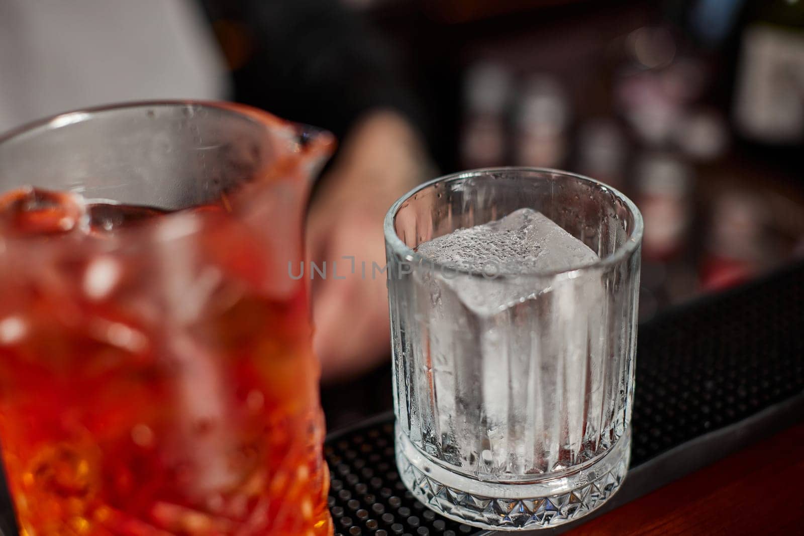 old fashioned cocktail with large piece of ice on the bar counter.