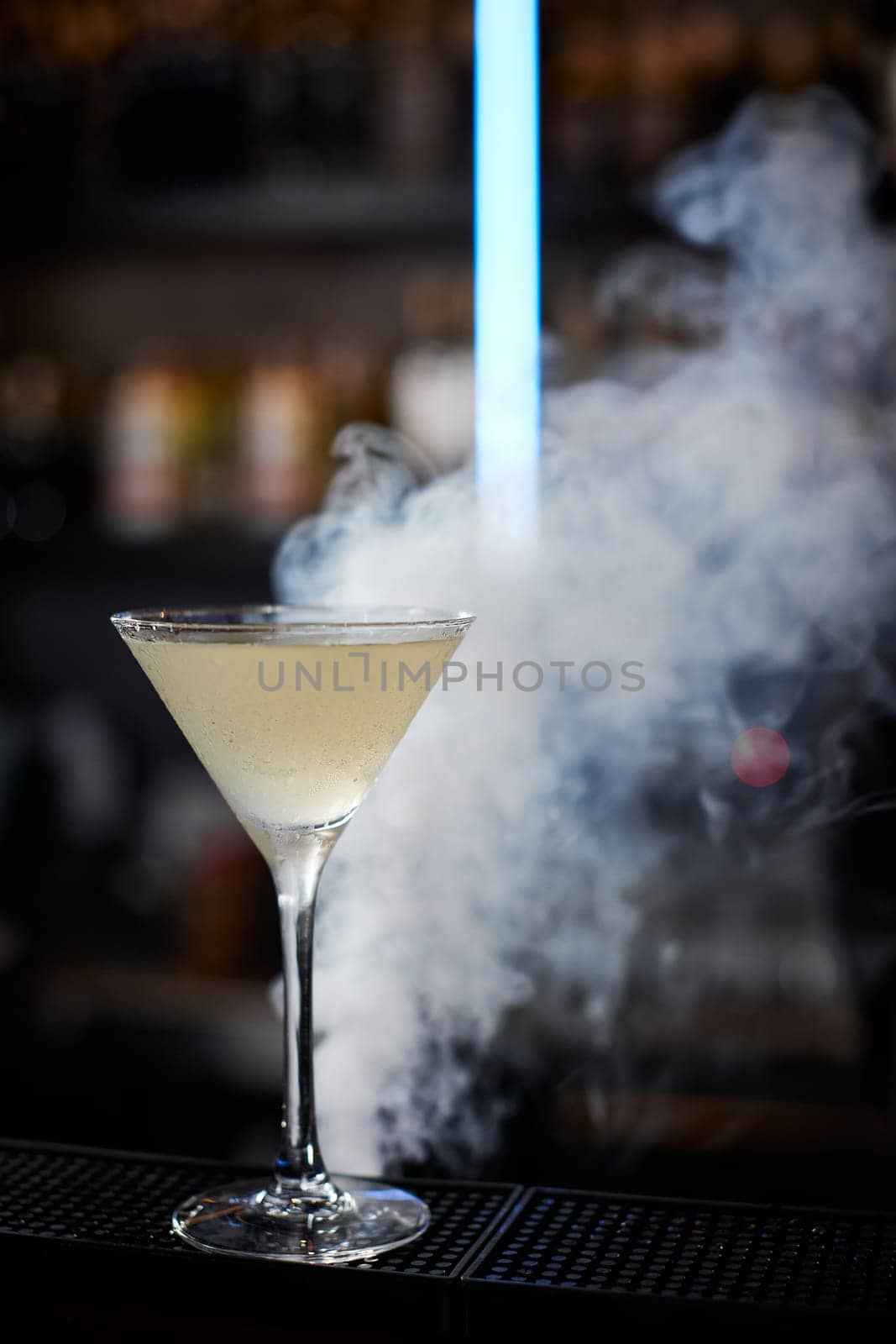 alcoholic cocktail with smoke at the bar. soft drink on the bar table.