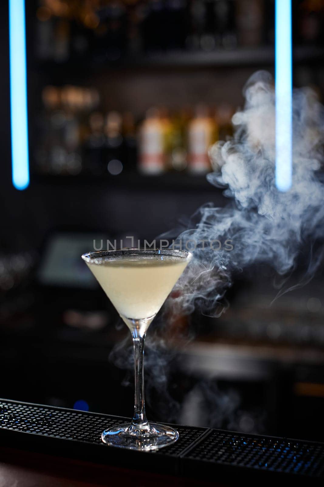 alcoholic cocktail with smoke at the bar. soft drink on the bar table.