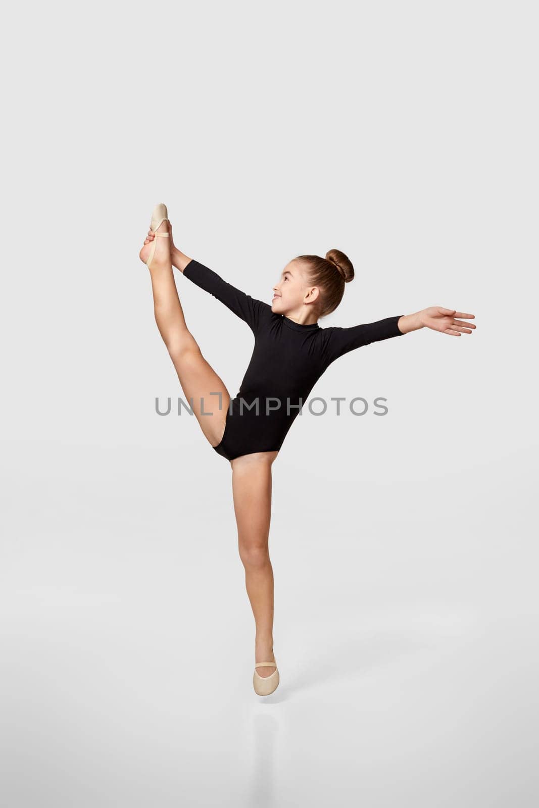 flexible little child girl in black sportswear perform transverse twine. Good stretching and gymnastics