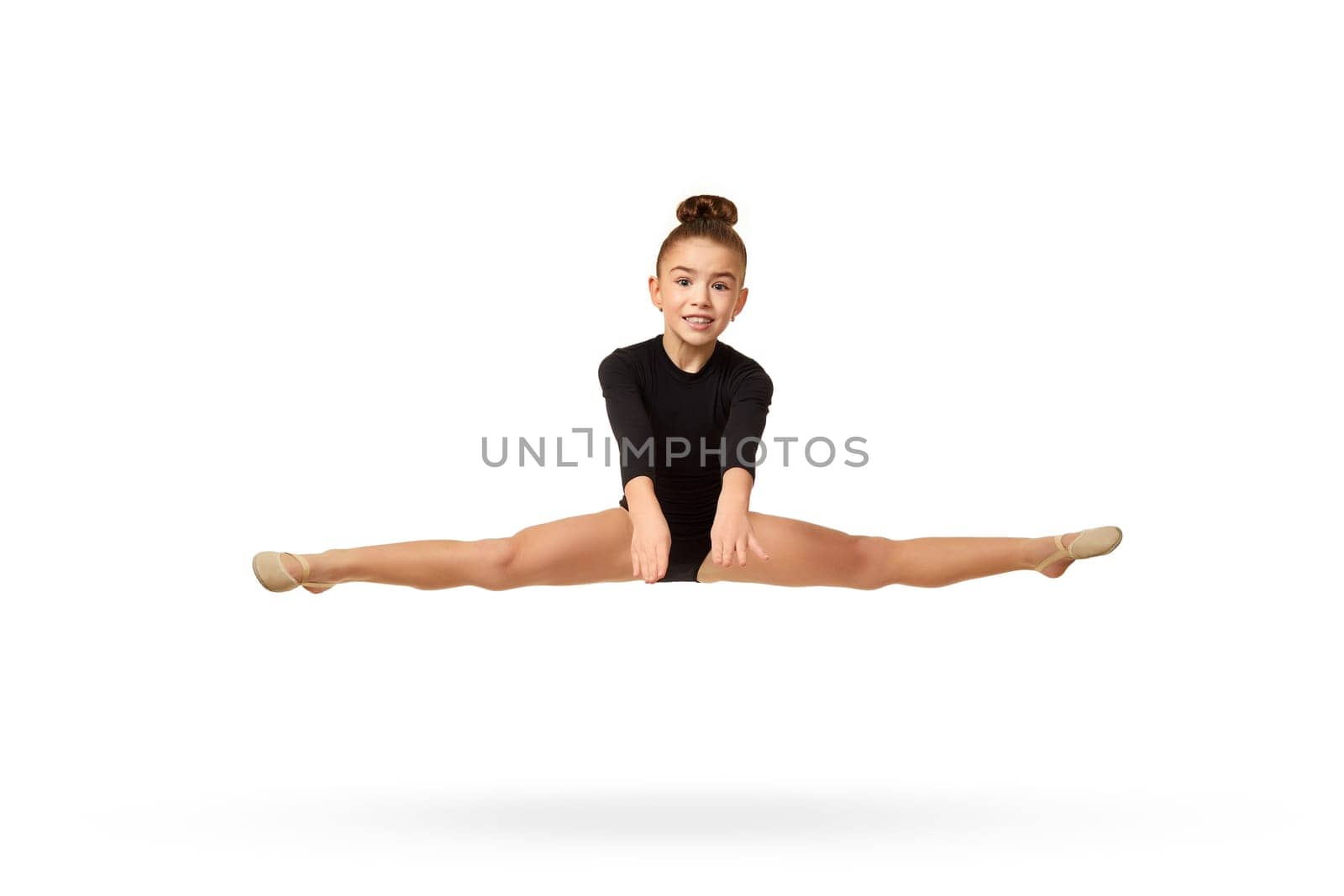 cute little child girl in black sportswear perform transverse twine on fly over white background. Good stretching and gymnastics