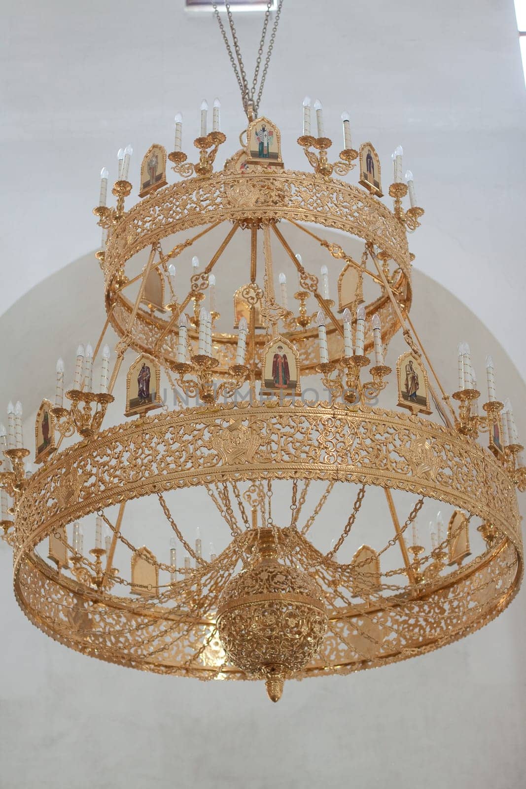 Ornate gold chandelier with candle holders in modern architecture.