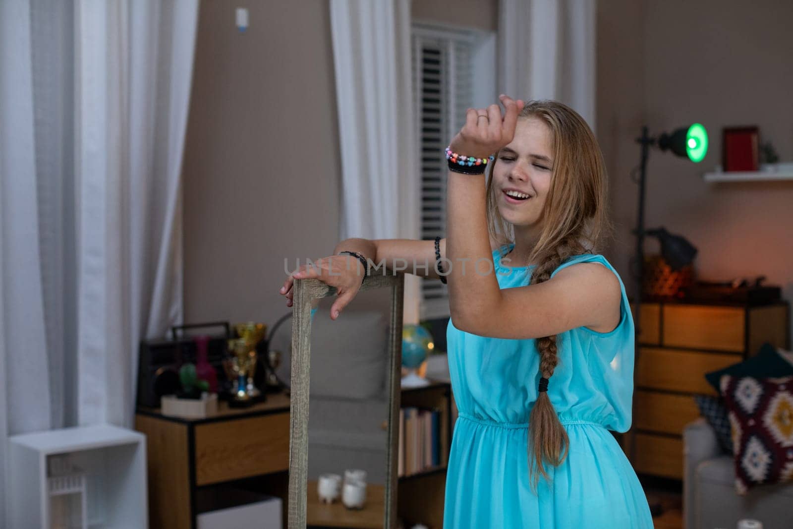 A cheerful girl in a lovely blue dress poses at home, creating a fun and warm atmosphere filled with joy