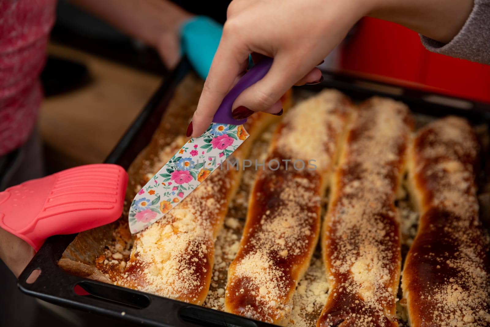A hand slices through cheesy enchiladas topped with rich sauce and melty cheese, ideal for sharing meals