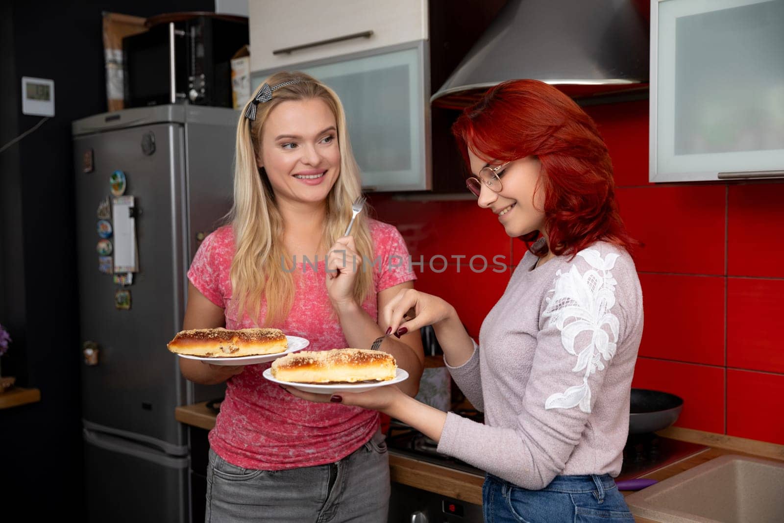 Two friends are sharing a delightful, funfilled moment as they prepare mouthwatering hot dogs in a vibrant kitchen