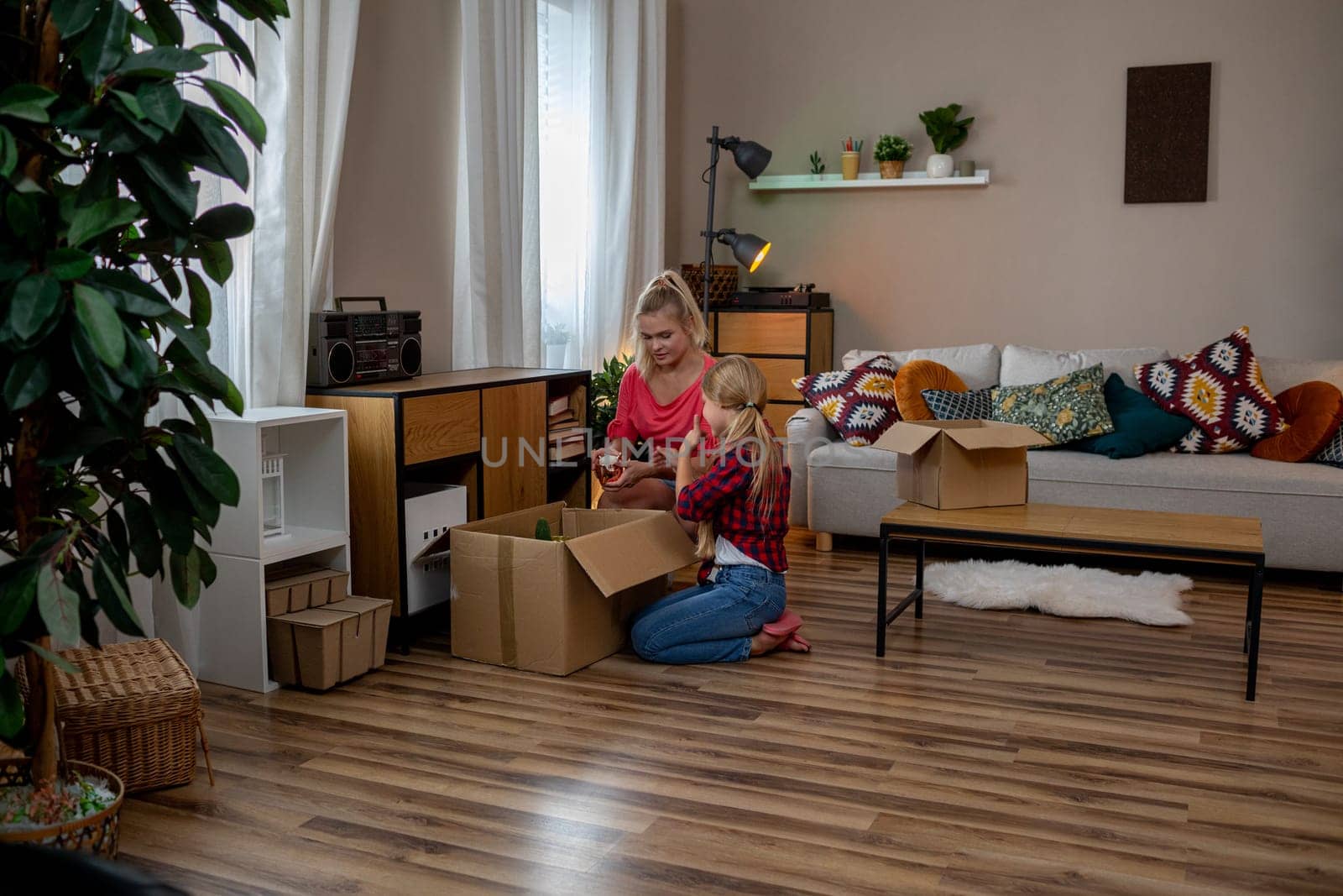 A woman carefully unpacks boxes in a bright, cozy living room, highlighting her organization skills