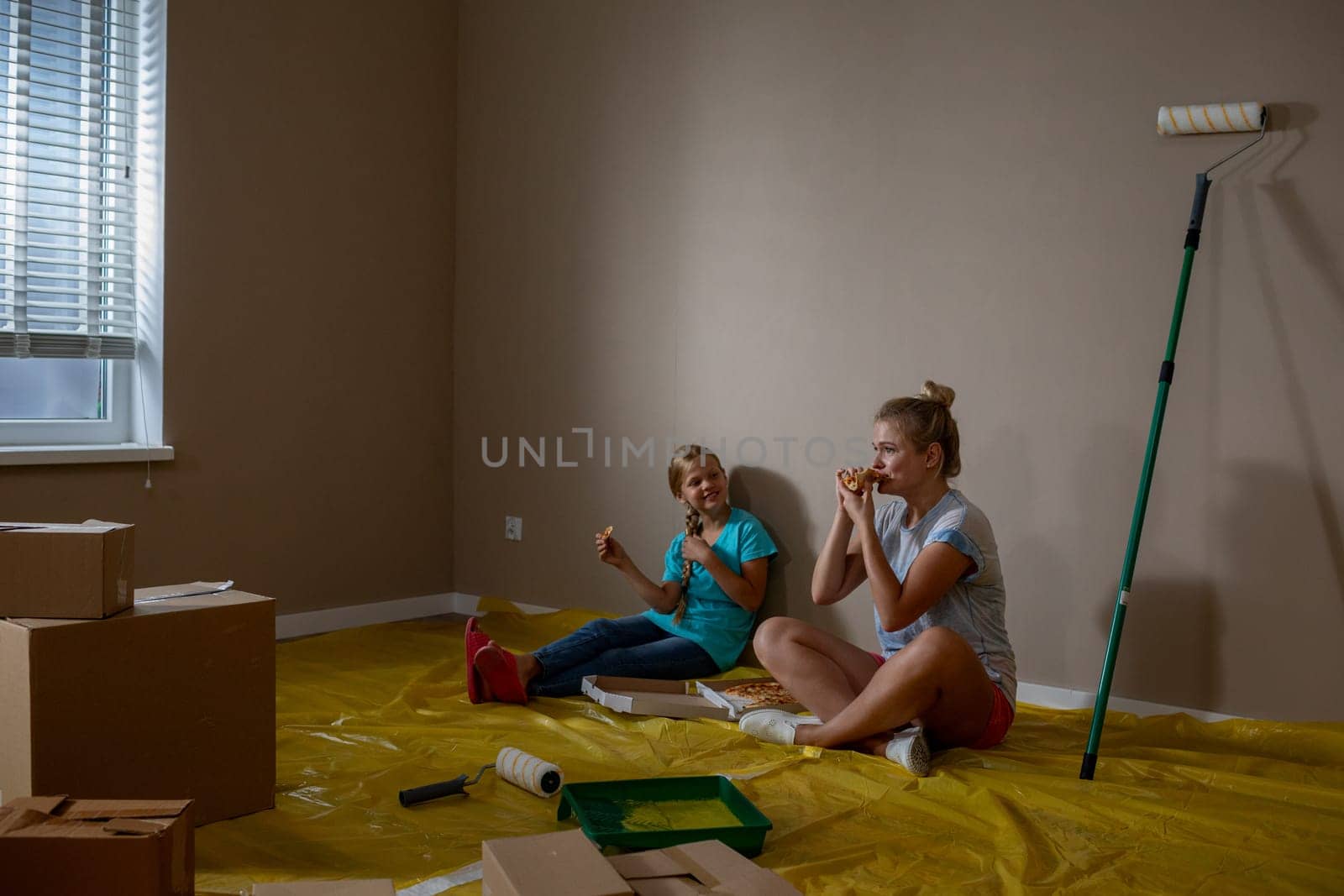 Two friends share laughter and joy while sitting on the floor during an exciting room renovation project