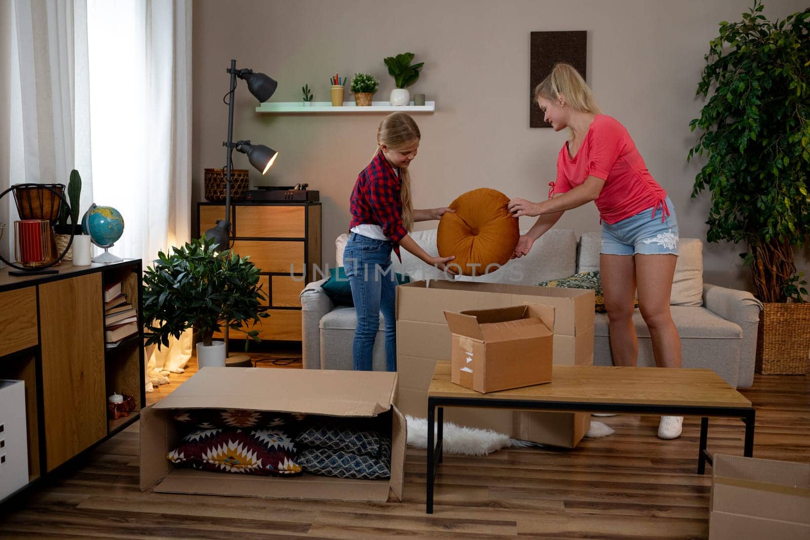 A cheerful family comes together to enjoy unpacking and organizing their new and cozy living room space