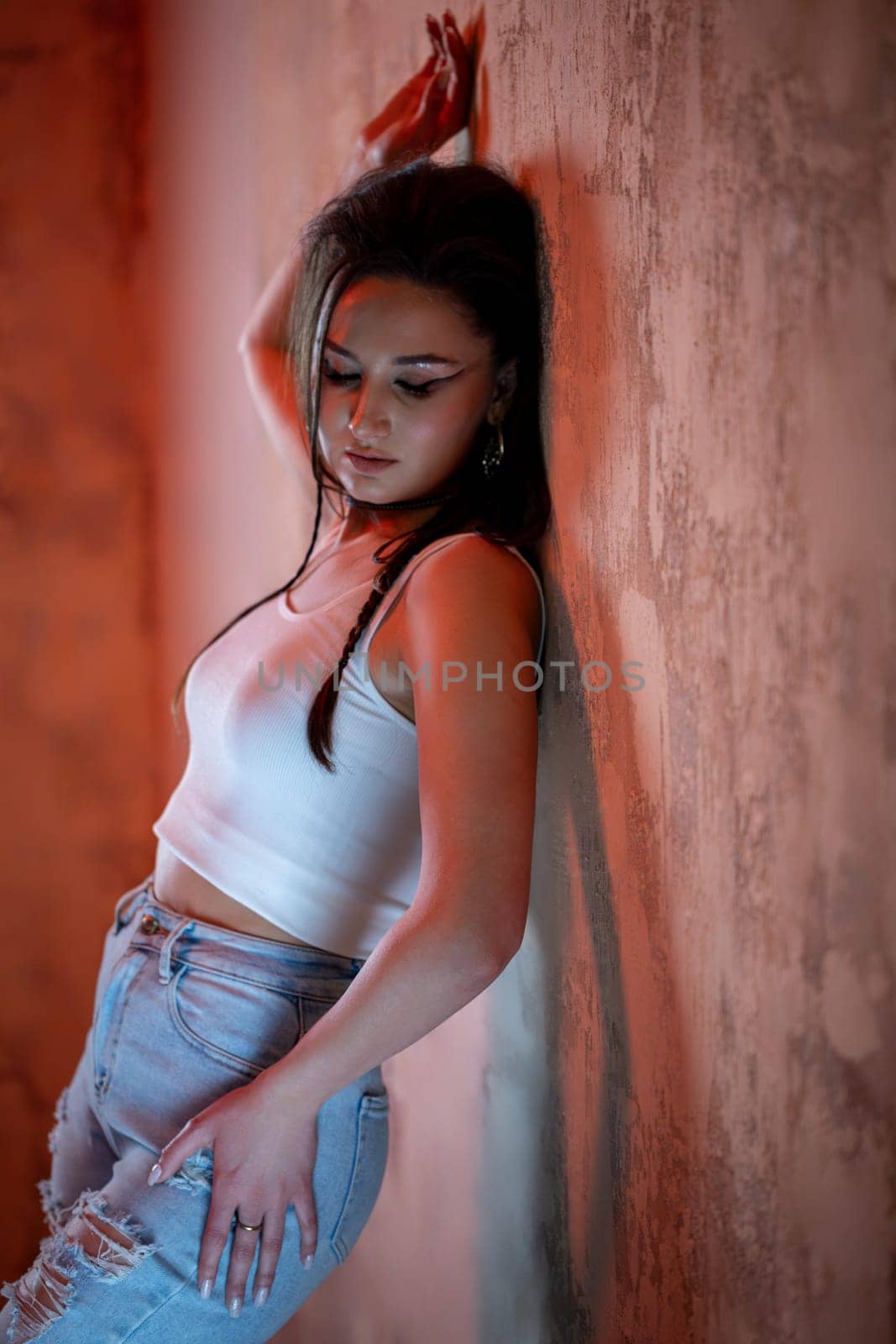 A chic model in a stylish outfit poses against a textured wall, showcasing urban fashion vibes dynamically