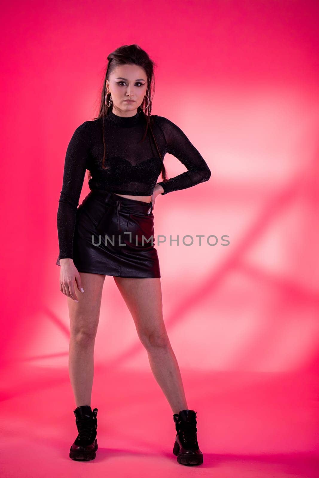 A stylish young model elegantly showcases modern fashion trends while posing against a bright pink backdrop