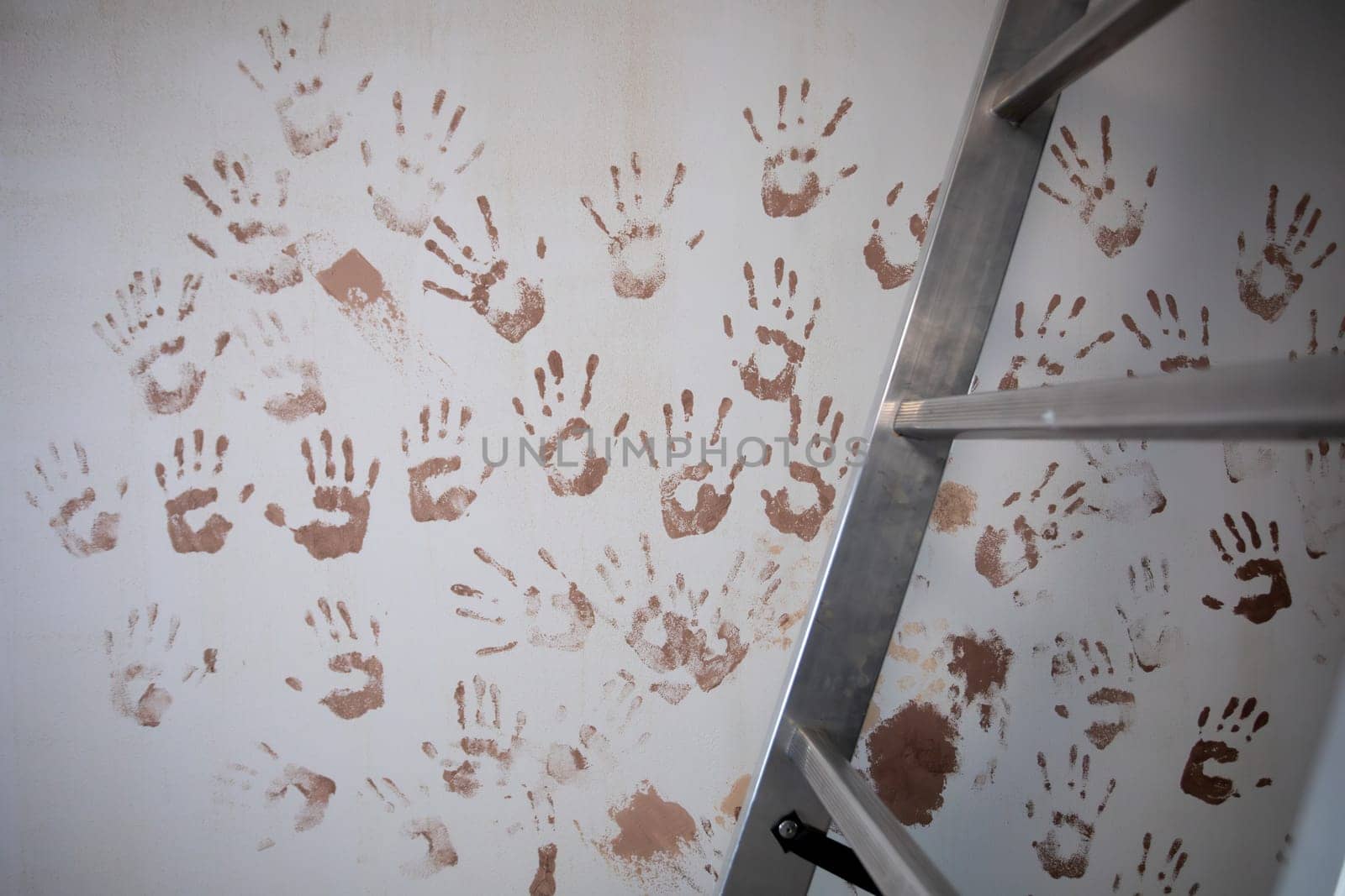 A colorful arrangement of vibrant handprints on a wall by a ladder, evoking creativity and expression