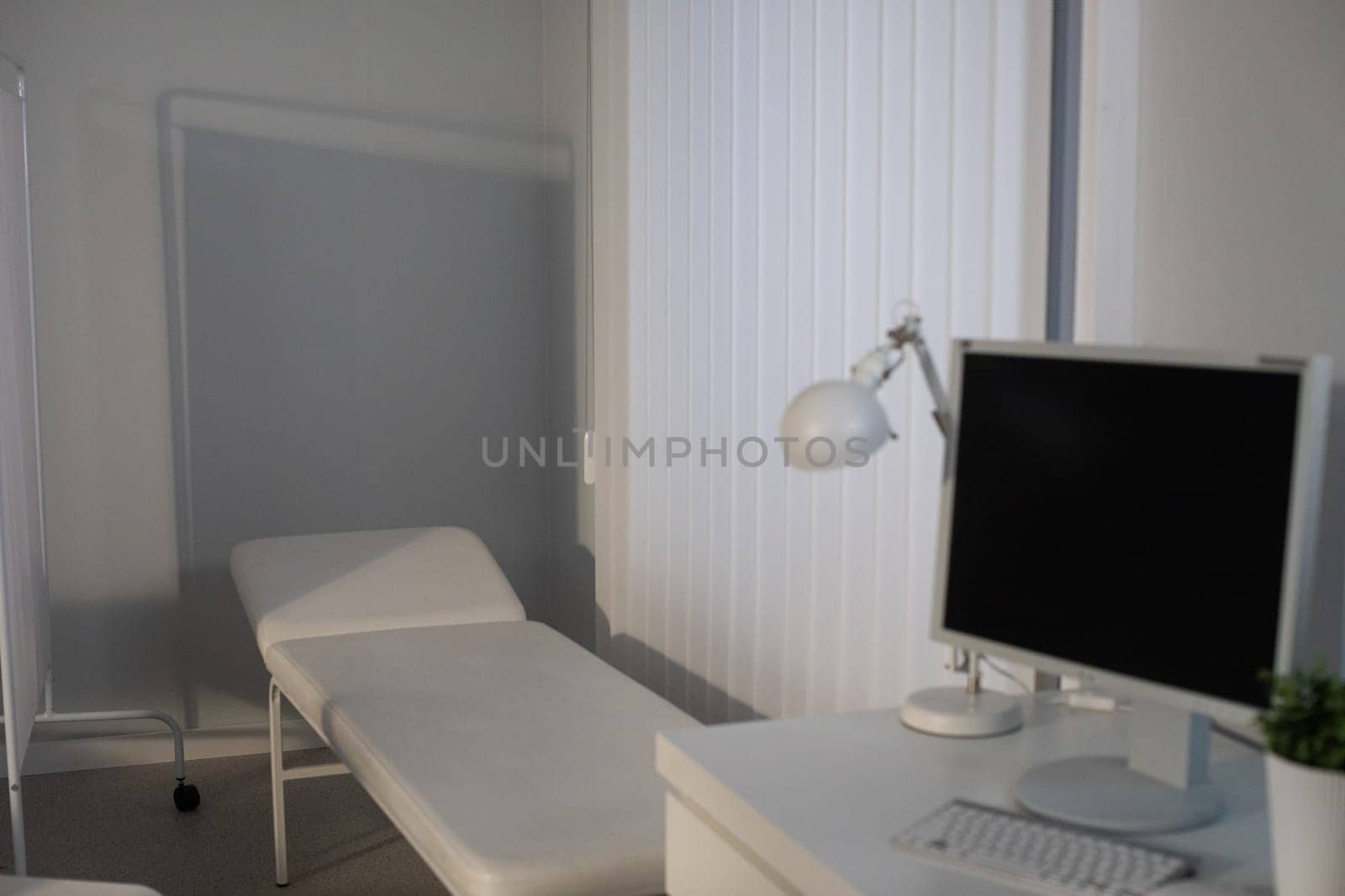 A calm and minimalist room that features a bed and a desk, illuminated by soft lighting and painted in neutral colors