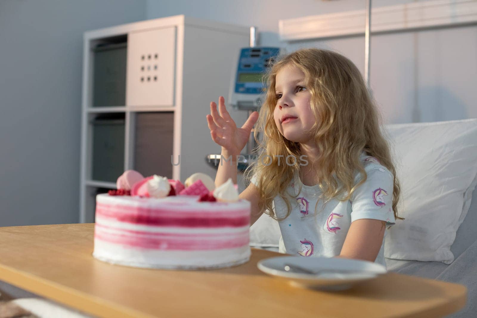 A young girl joyfully enjoys a delightful cake celebration within a hospital setting, symbolizing hope and resilience