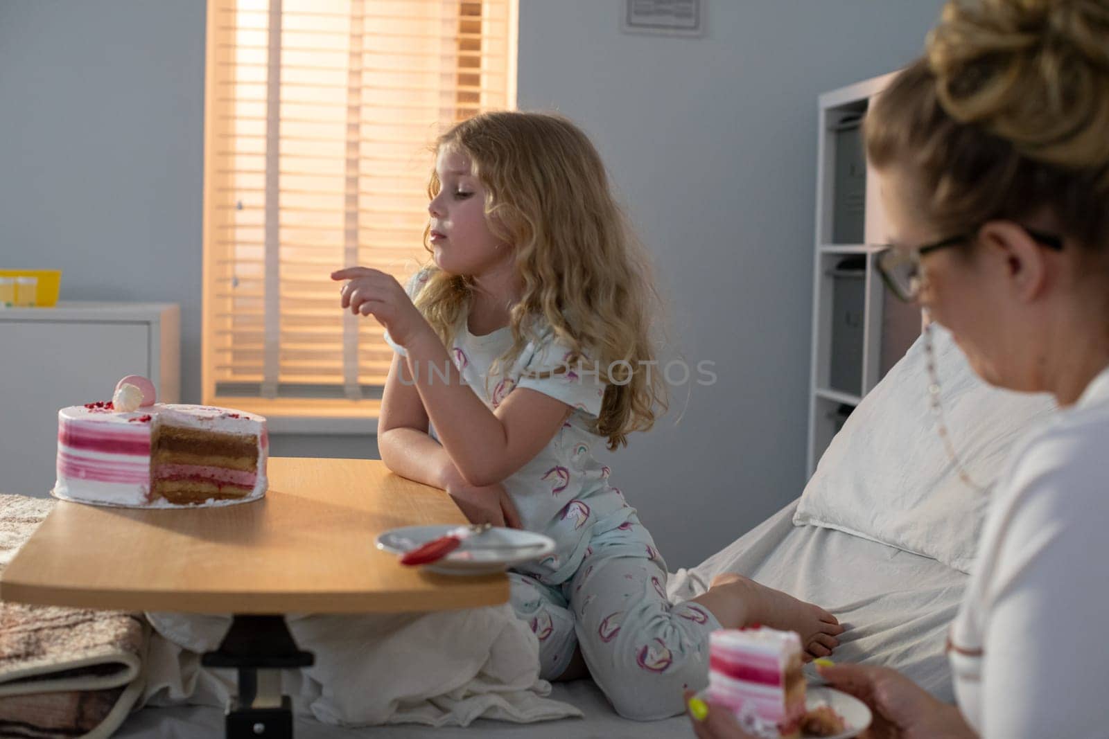A joyful child and cheerful adult enjoy desserts in a bright room filled with laughter, sharing precious moments