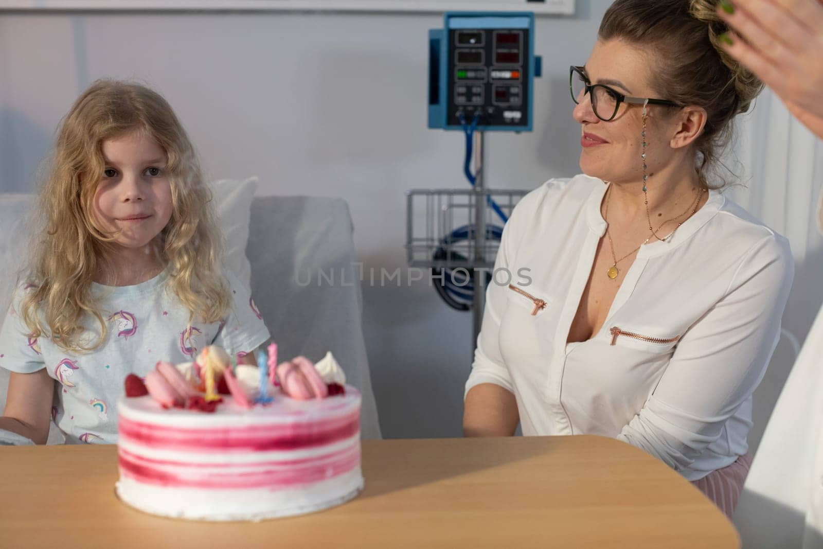 A heartwarming moment unfolds in a hospital as a child and an adult joyfully celebrate with a delightful birthday cake