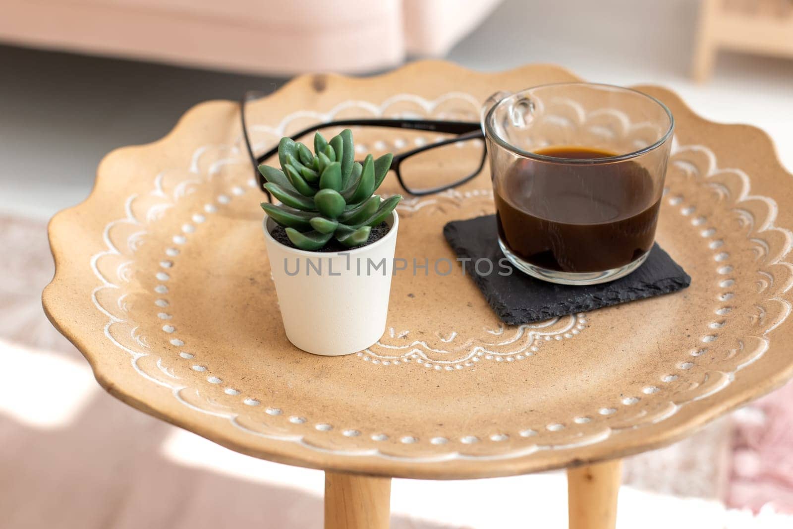 A succulent and a cup of black coffee stand on a small ceramic coffee table, with oriental ornaments.