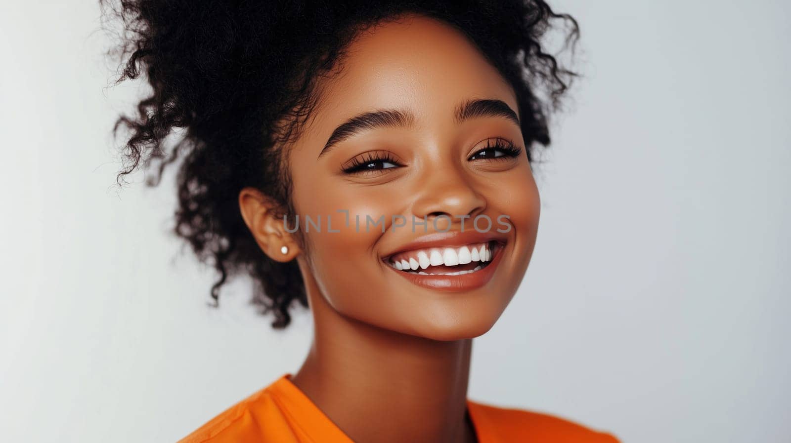 Portrait of happy young black American woman smiles, joyful African girl looking at camera standing on gray background