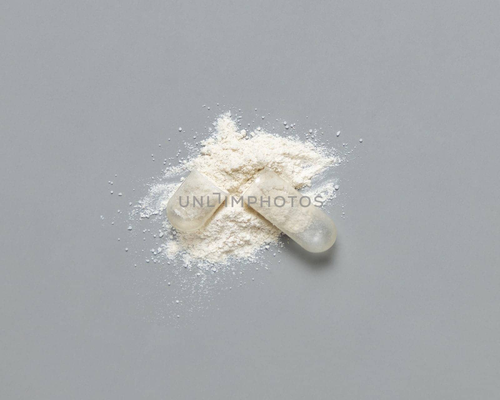 Opened Medical capsule to show white powder on grey top view. Alternative preventive medicine and healthcare, taking dietary supplements and vitamins