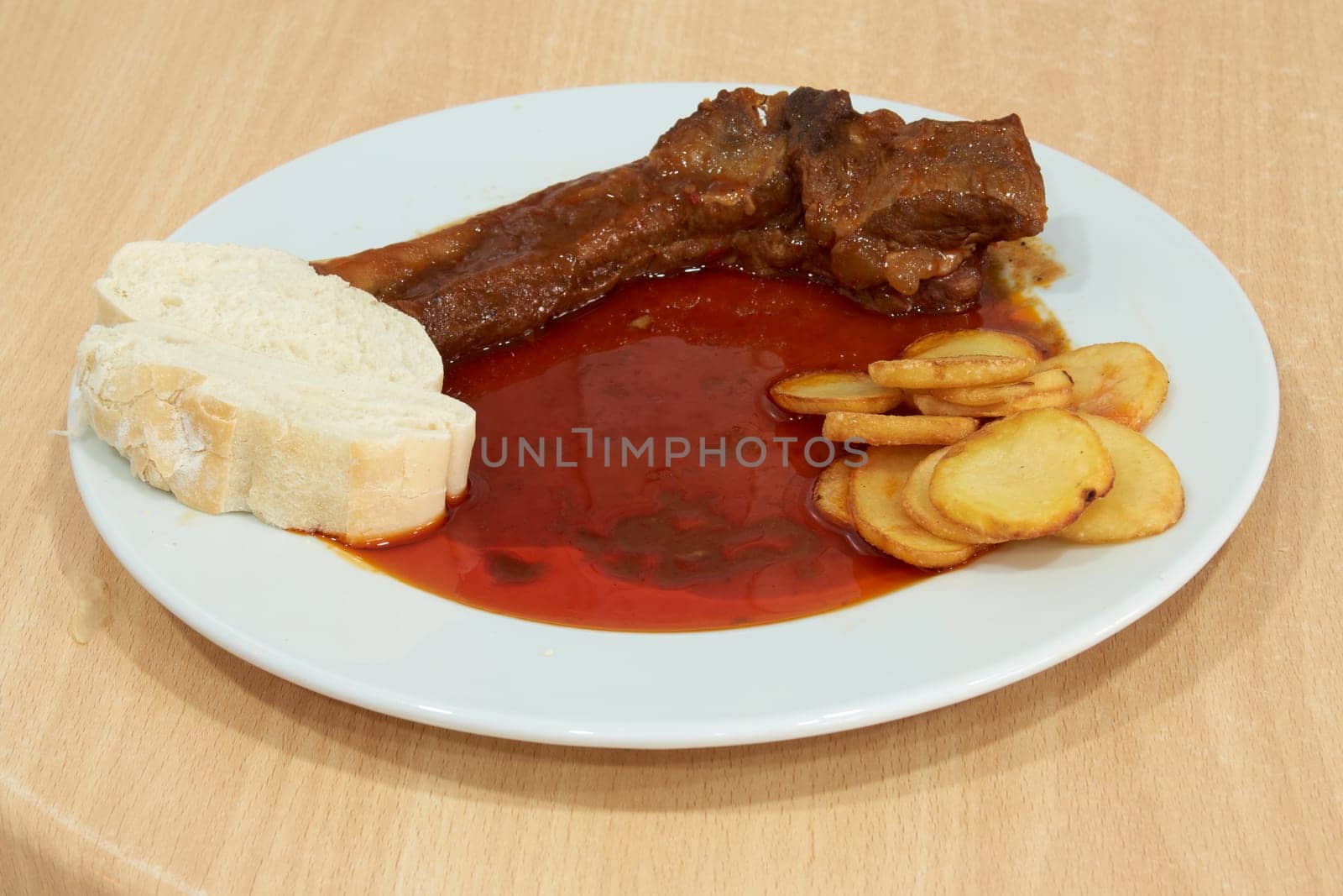 A plate of food with a piece of meat and potatoes on it. The plate is white and the meat is brown