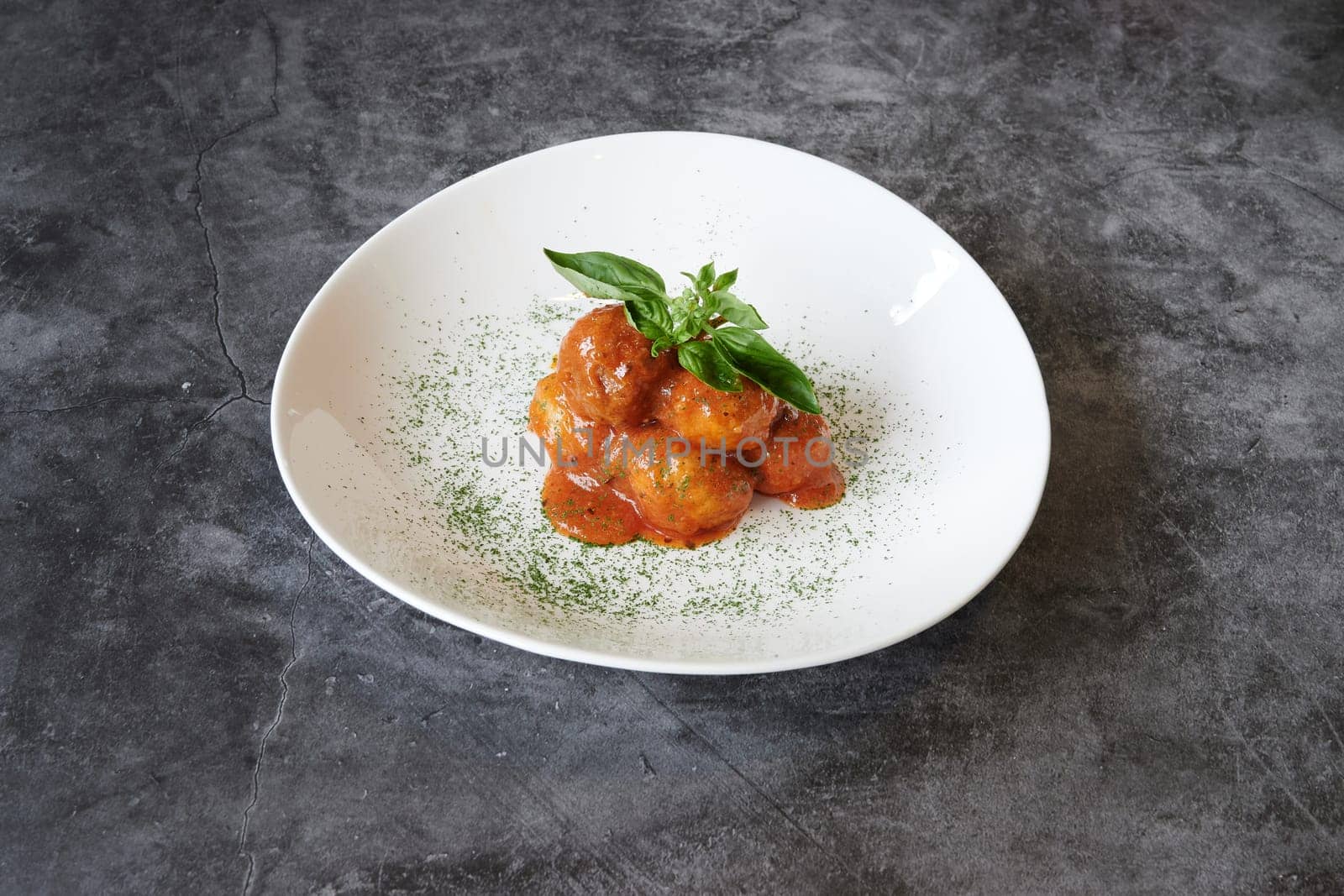 A plate of food with a green leaf on top. The plate is white and the food is red