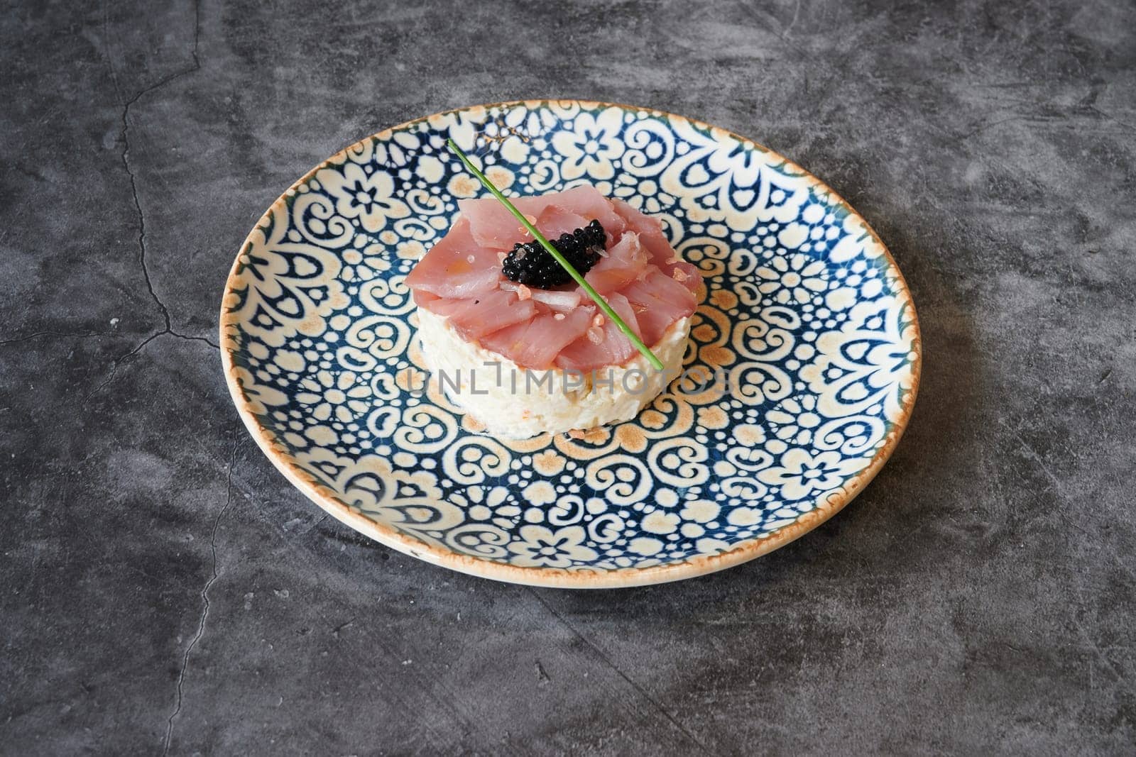 A plate of food with a small piece of meat and a small piece of blackberry. The plate is blue and white