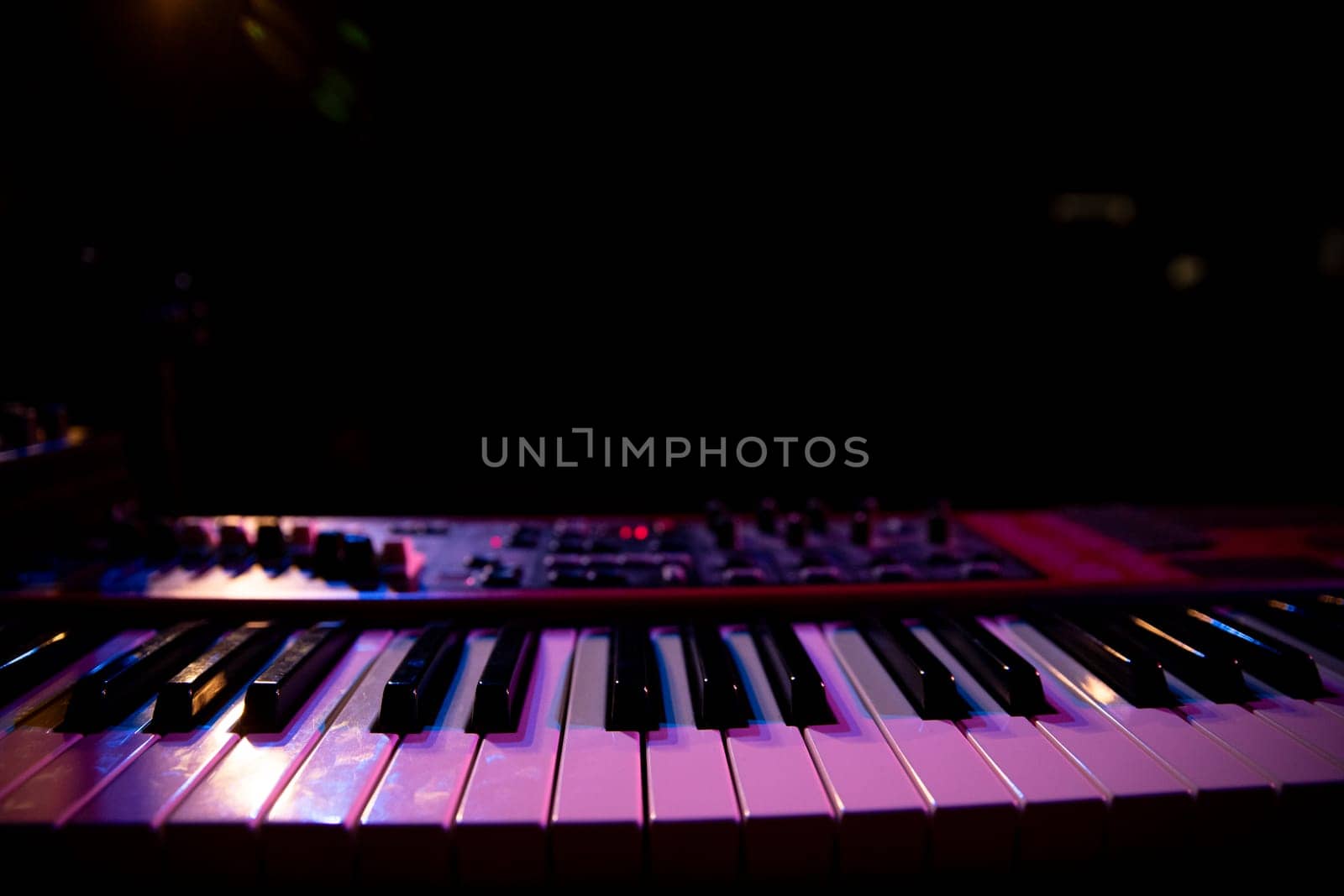 This is a closeup view of piano keys that are beautifully illuminated in low light, capturing a rich musical ambiance