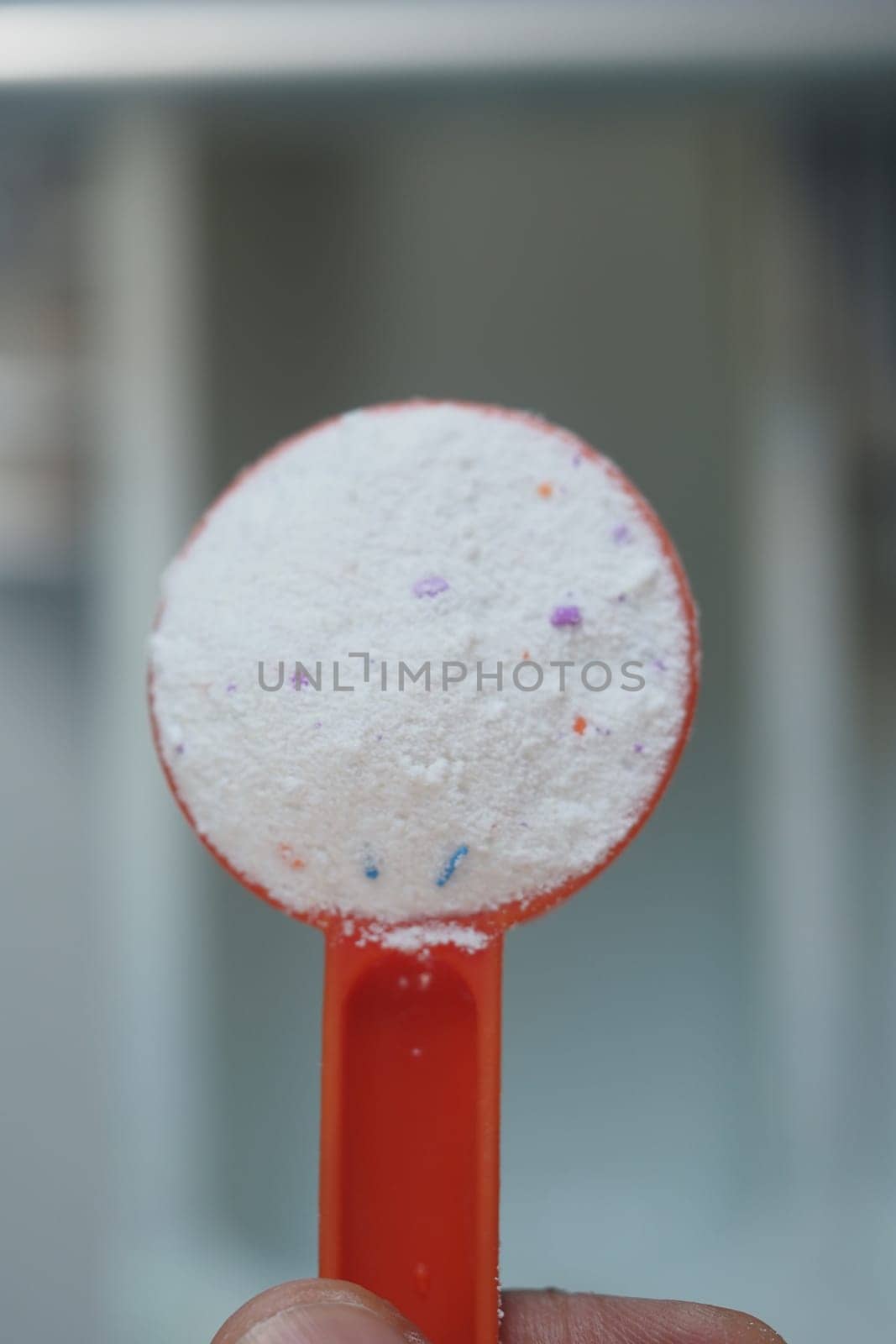 Preparing to do laundry by measuring detergent with a scoop.