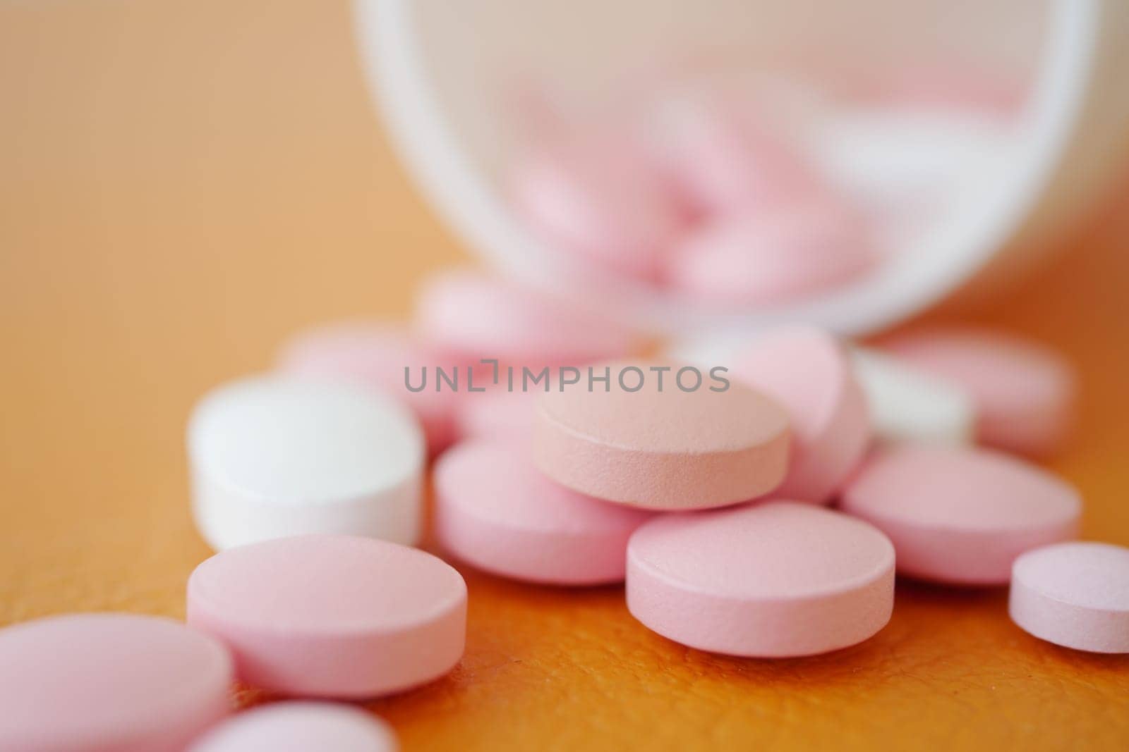 Pink and white tablets are spilled across a flat surface.