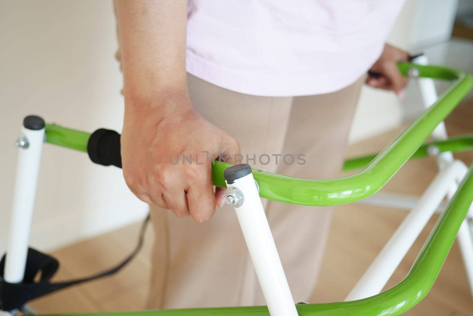 An individual holds a green mobility aid in a well-lit room.