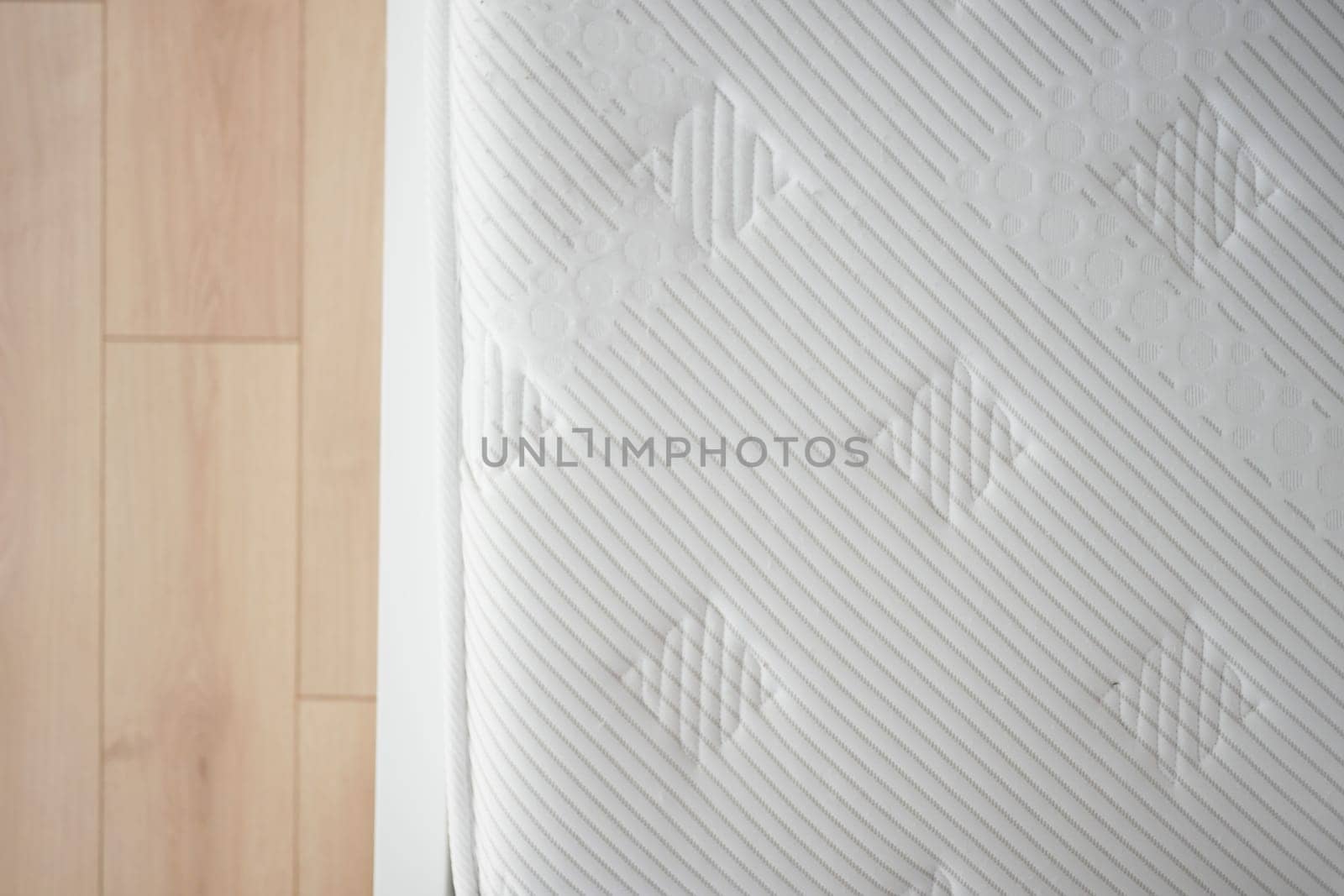 Close view of a mattress placed on a wooden floor of a cozy bedroom.