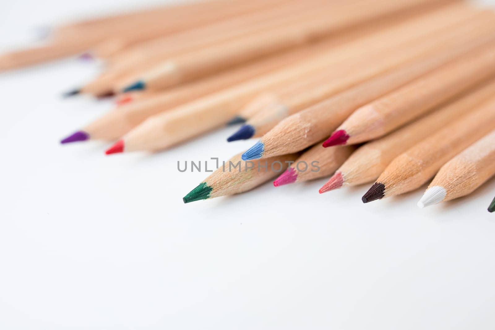 Colorful wooden pencils on white surface in assorted shades.