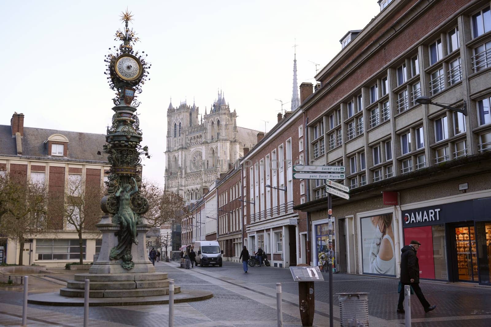 The ornate clock tower stands in the foreground of Amiens. France 17.02.2025, with the majestic Gothic cathedral rising in the background.