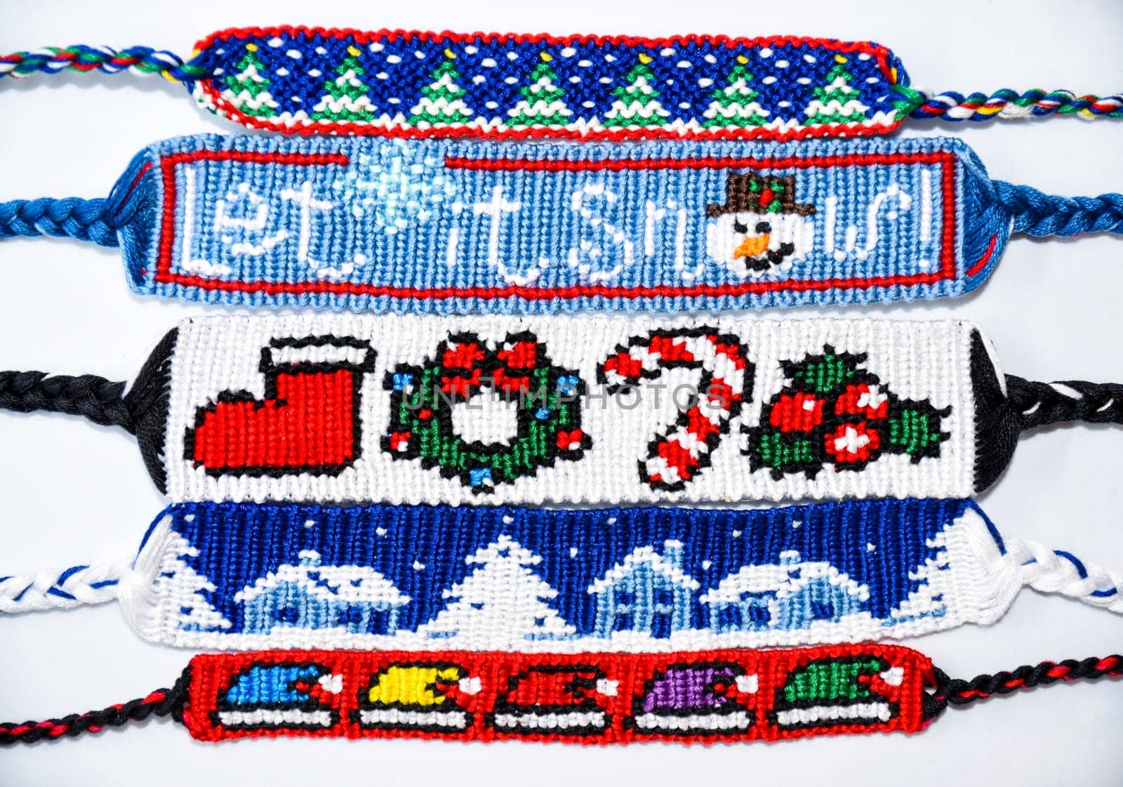 Woven friendship bracelets with alpha patterns Christmas and New Year, handmade of thread on white background. DIY New Year gift idea