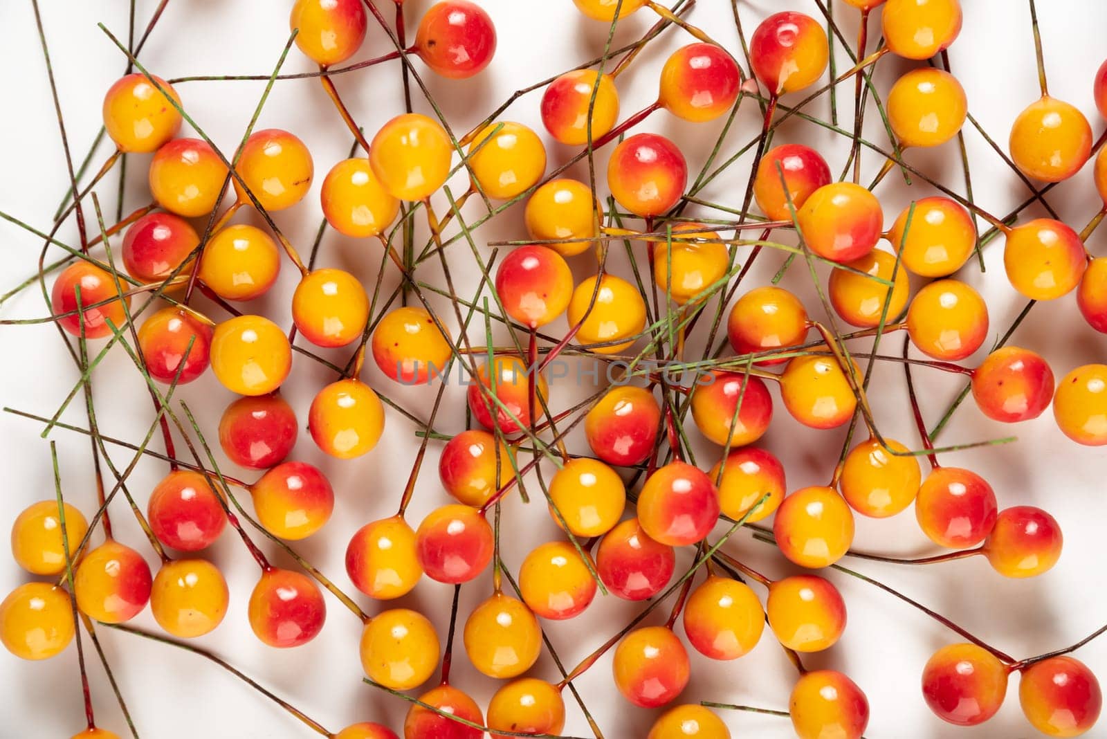 Artificial berries on a wire for needlework and decoration of gifts, wreaths on white background