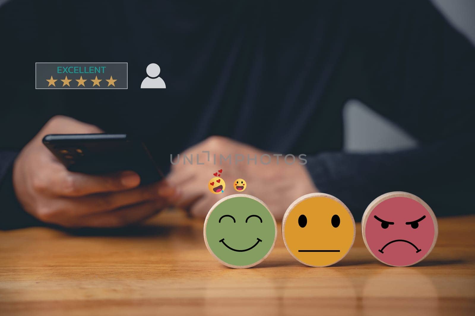 Man's using smartphone choosing a smiley face on a wooden block, evaluating customer experience. Surveying satisfaction with business services for excellent rating.