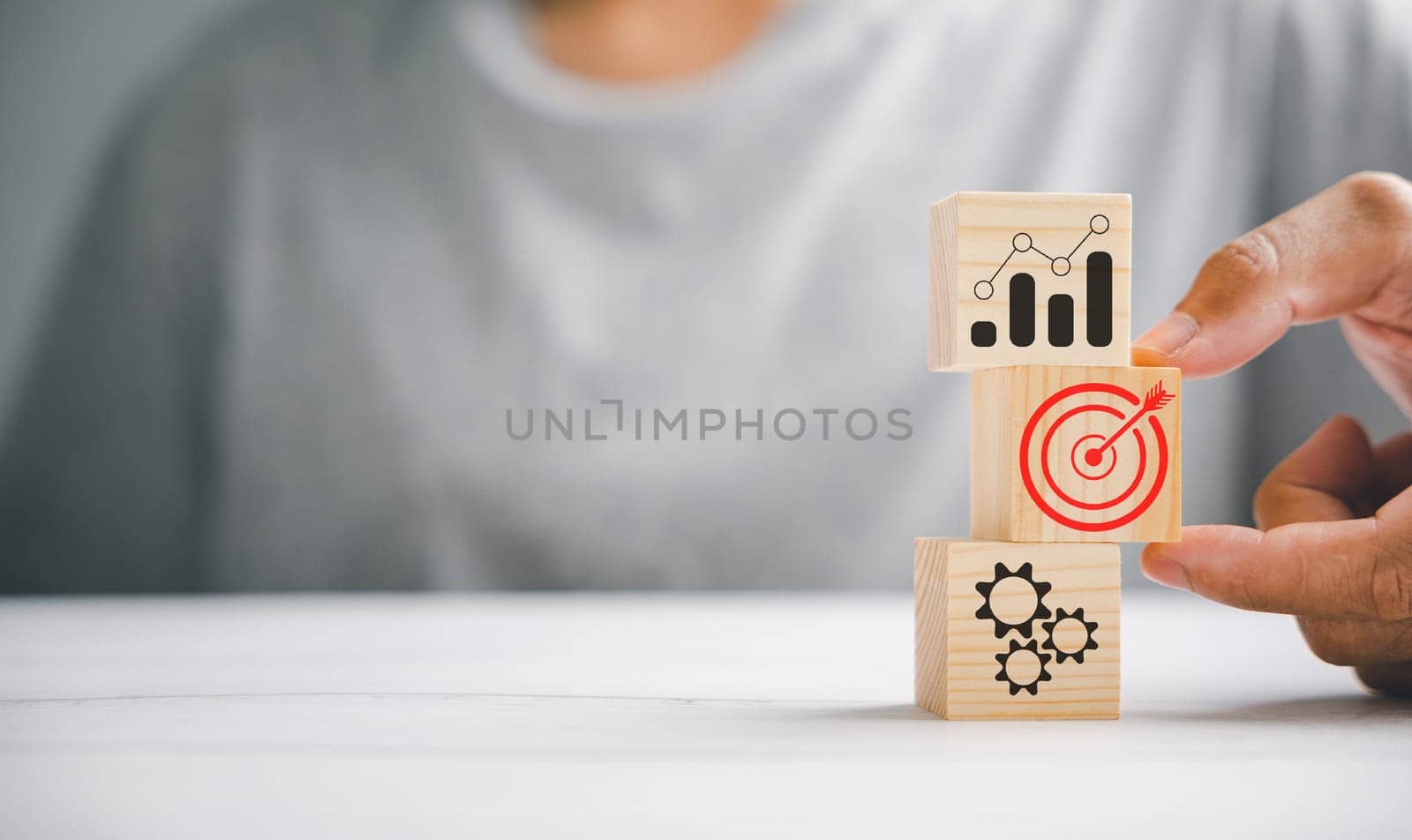 Wood block stacking by hand, showcasing the business strategy and action plan. Targeting the business concept. Conceptual representation of growth and achievement.
