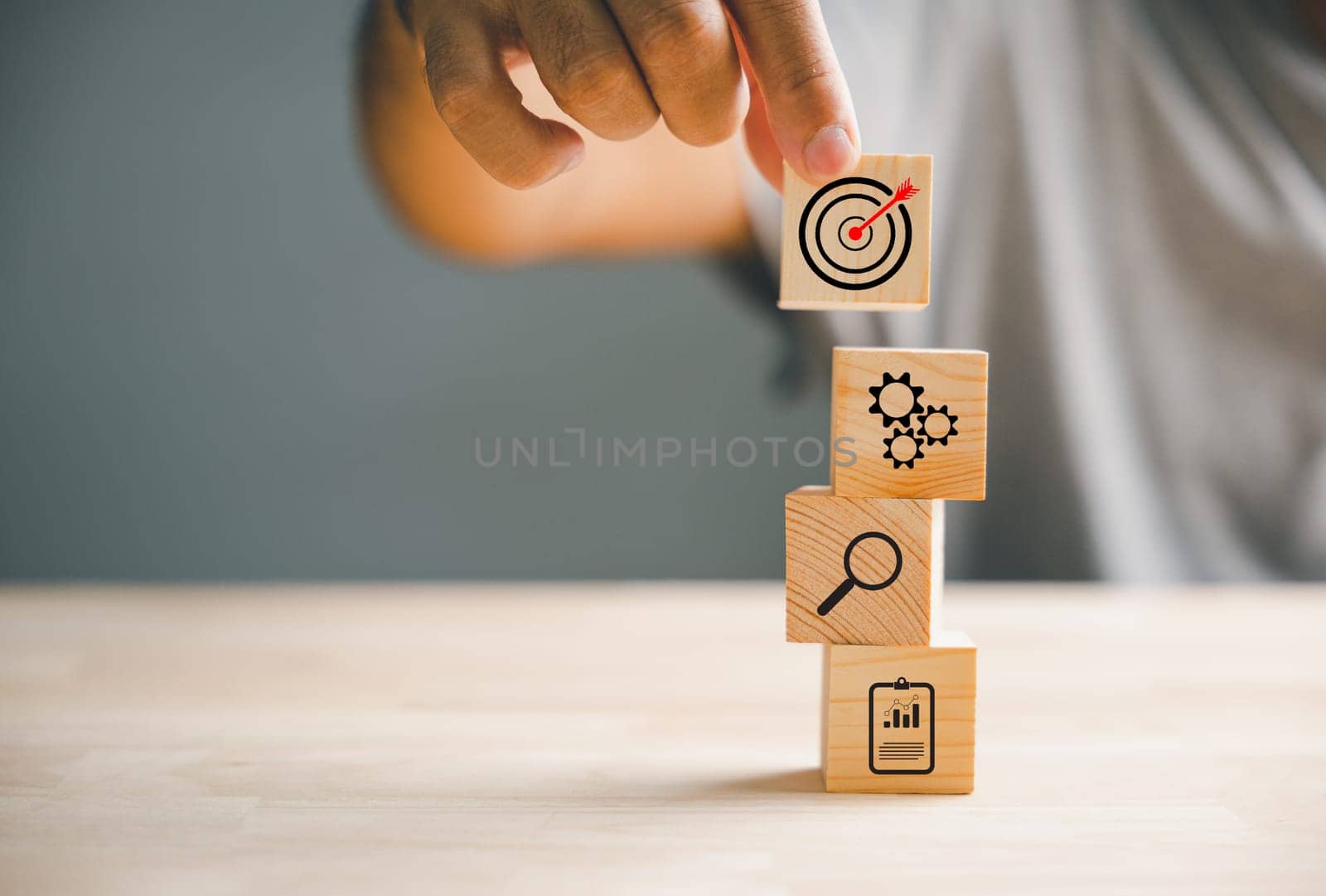 Businessman's hand arranging wood blocks with precision, depicting a business strategy and Action plan. This image represents the concept of business development and success.