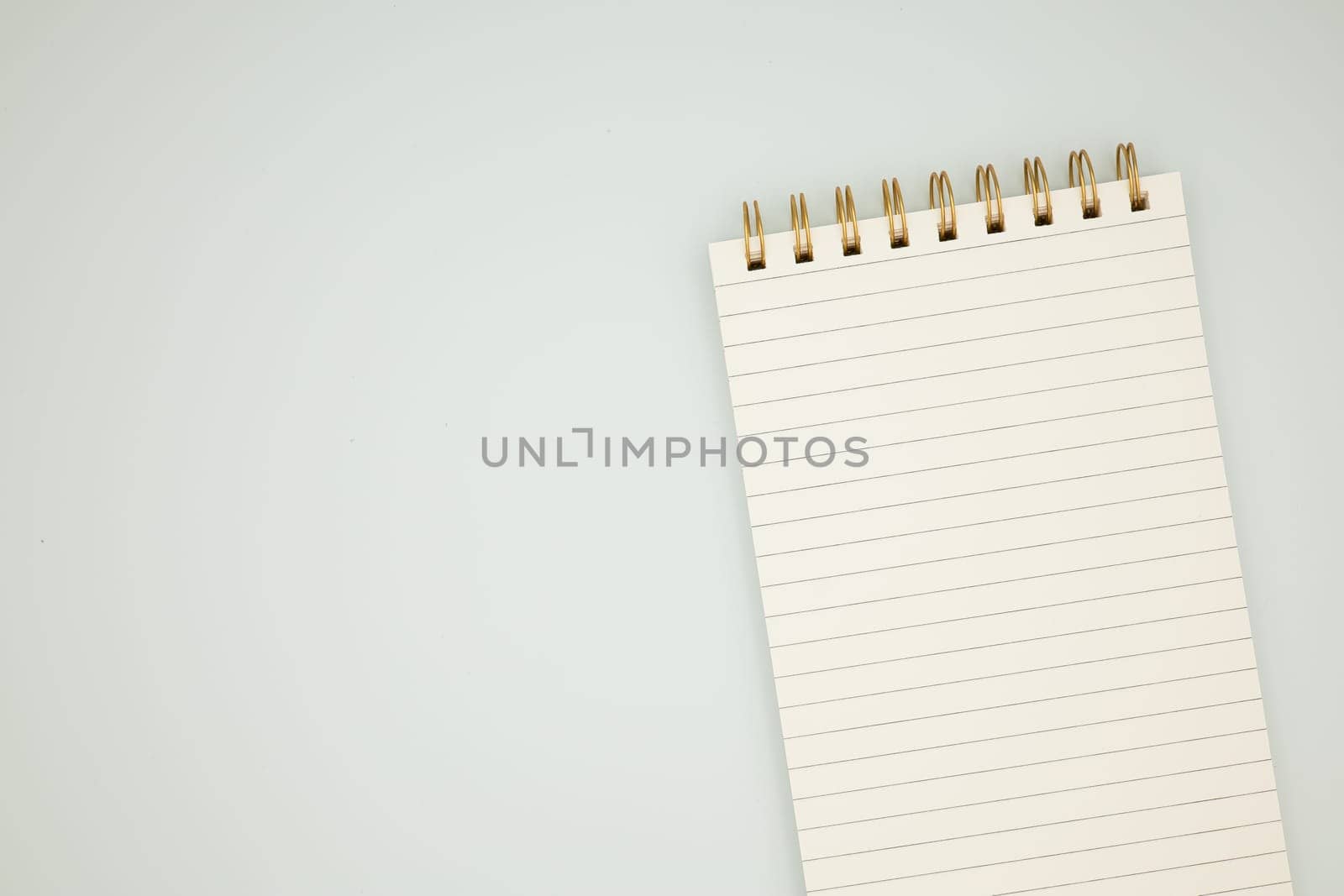 Spiral notepad with blank lined pages on light background.