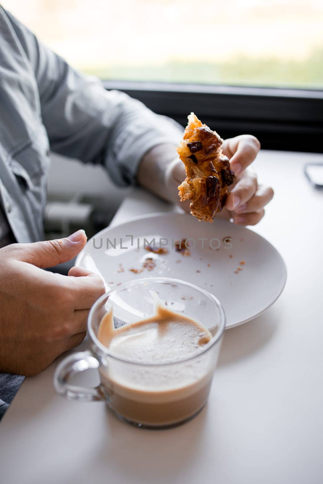 Adult male enjoying pastry and coffee in casual setting.