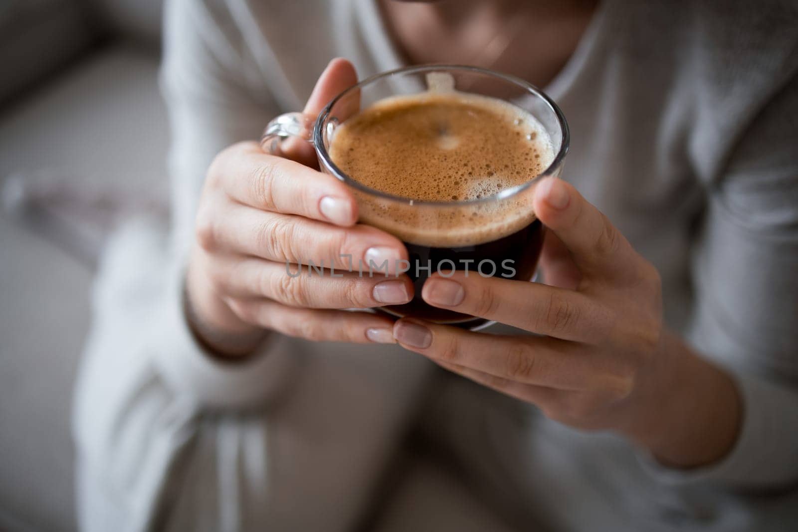 Female hands holding a cup of freshly brewed coffee at home.