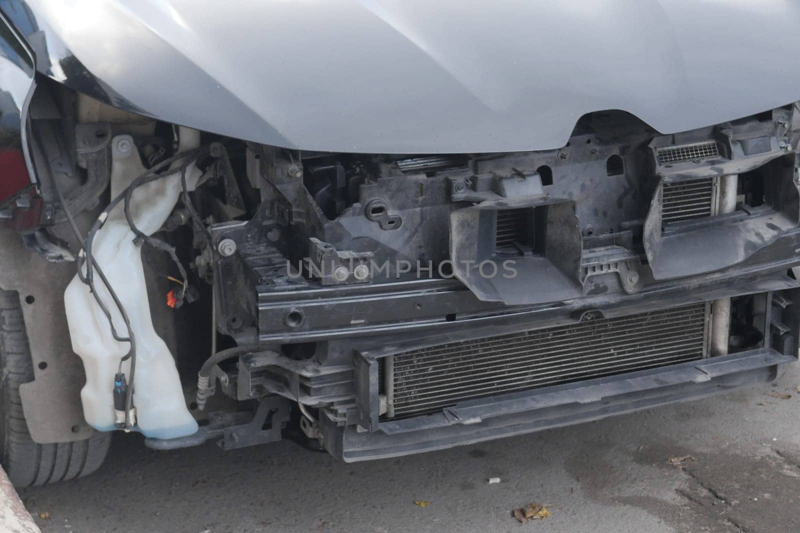 Mechanics work on dismantled car, revealing engine components and parts.