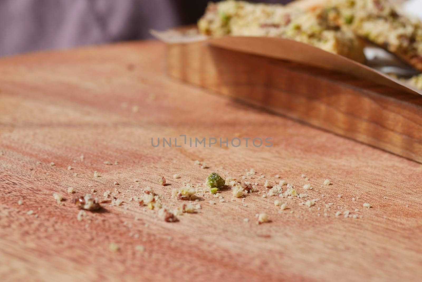 Crumbs are left behind on a wooden surface after enjoying a treat.