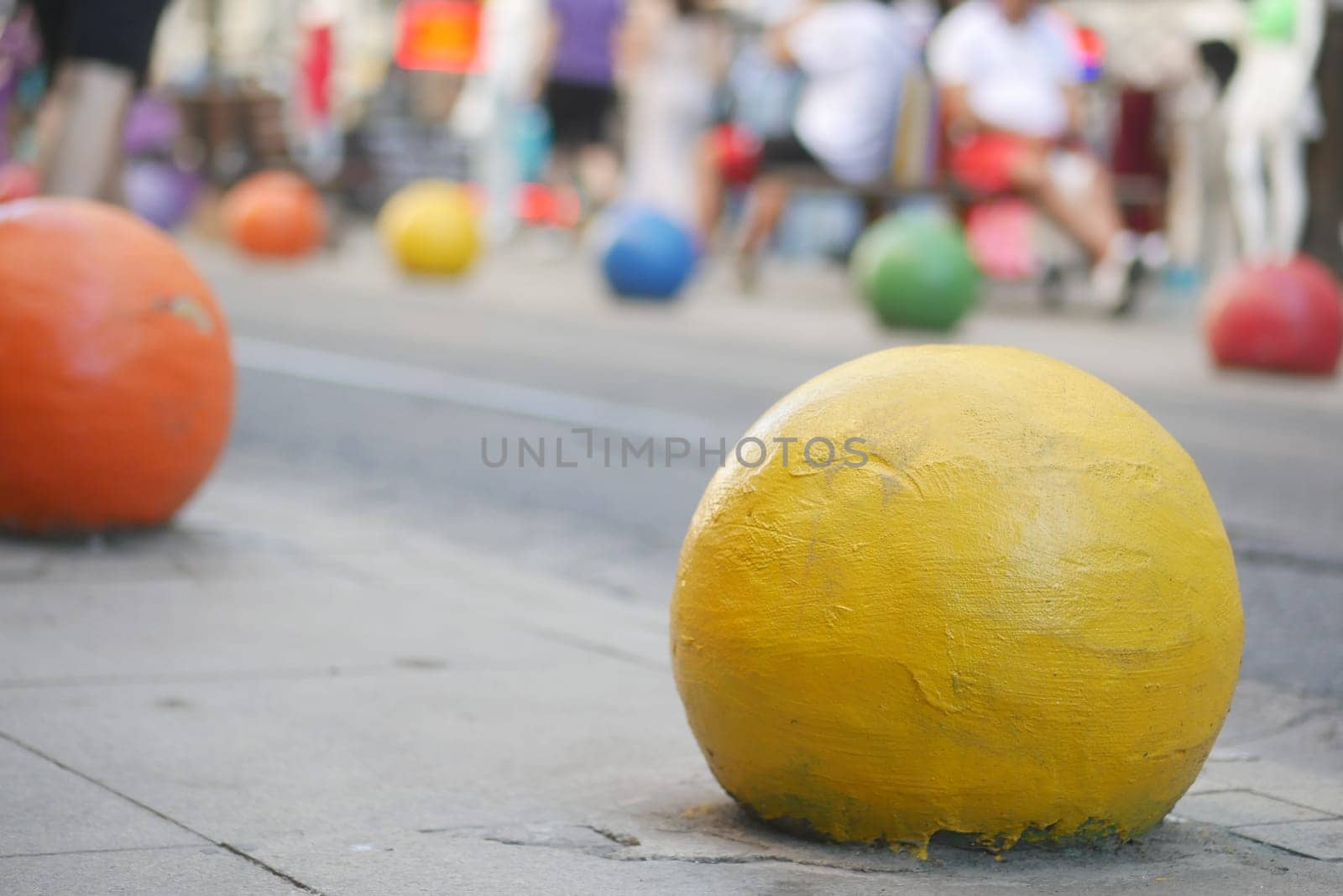 Brightly colored balls are spread across the pavement in a lively urban setting.