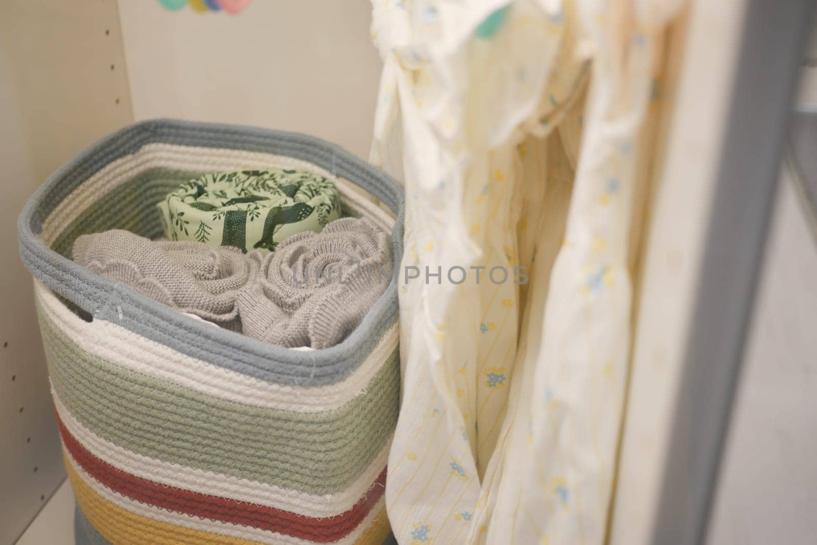 Neatly arranged towels in a colorful basket beside hanging fabric.