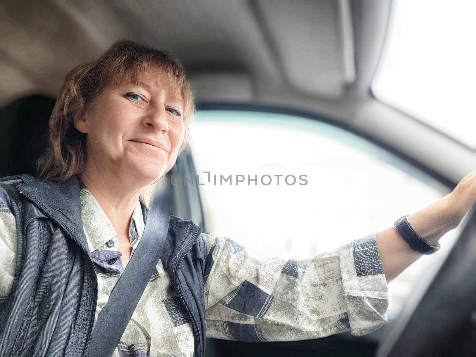 A middle-aged woman enjoys driving while embarking on a travel excursion.