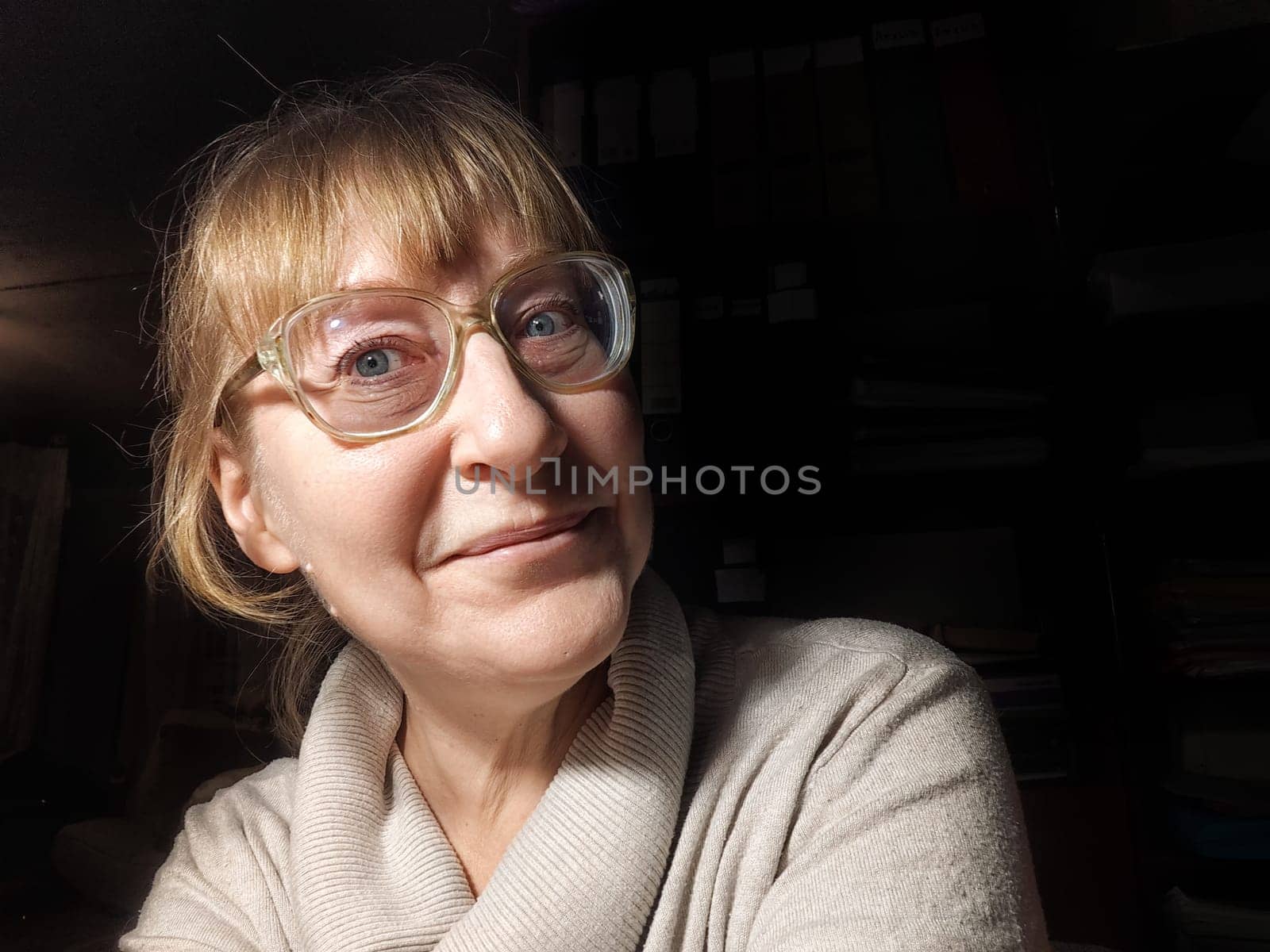 A 50-year-old woman captures a playful selfie while showcasing her adorable personality in a warm and inviting space.