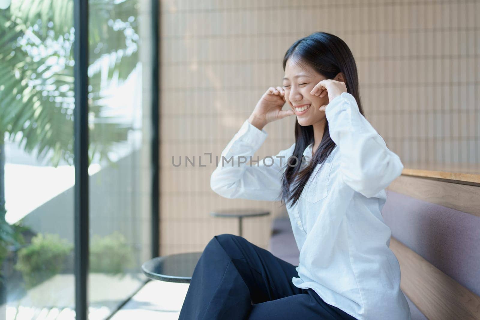 Joyful young woman enjoying moments of relaxation in a modern indoor space with natural light and greenery.