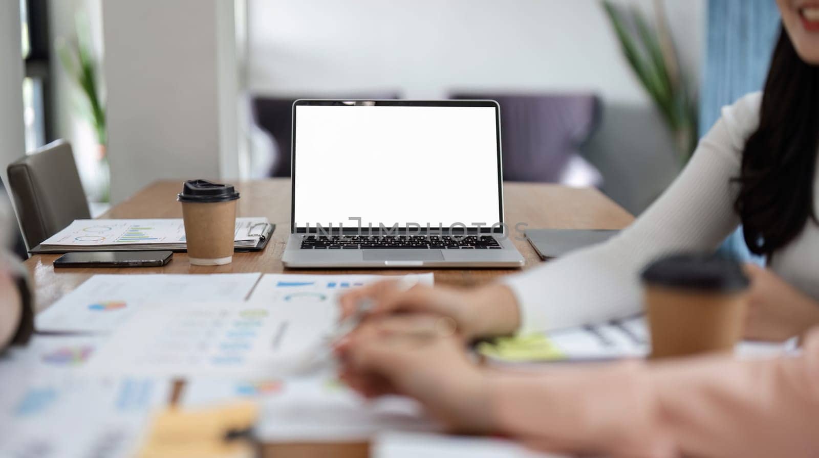 A team of women analyze financial documents and engage in a productive discussion during an office meeting, showcasing teamwork and collaboration.