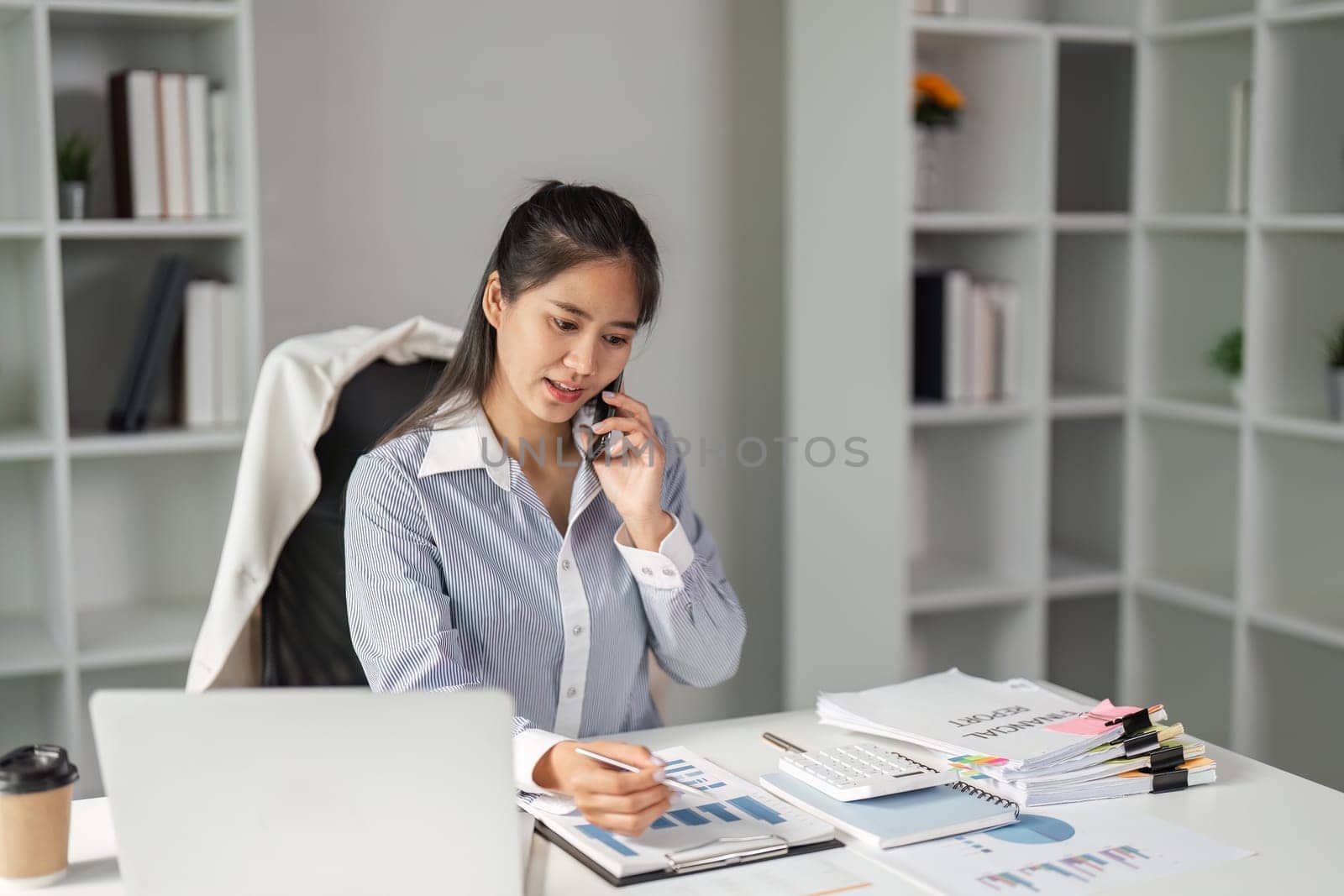 A dedicated finance worker reviews charts and data while on a phone call, showcasing multitasking in a professional environment.