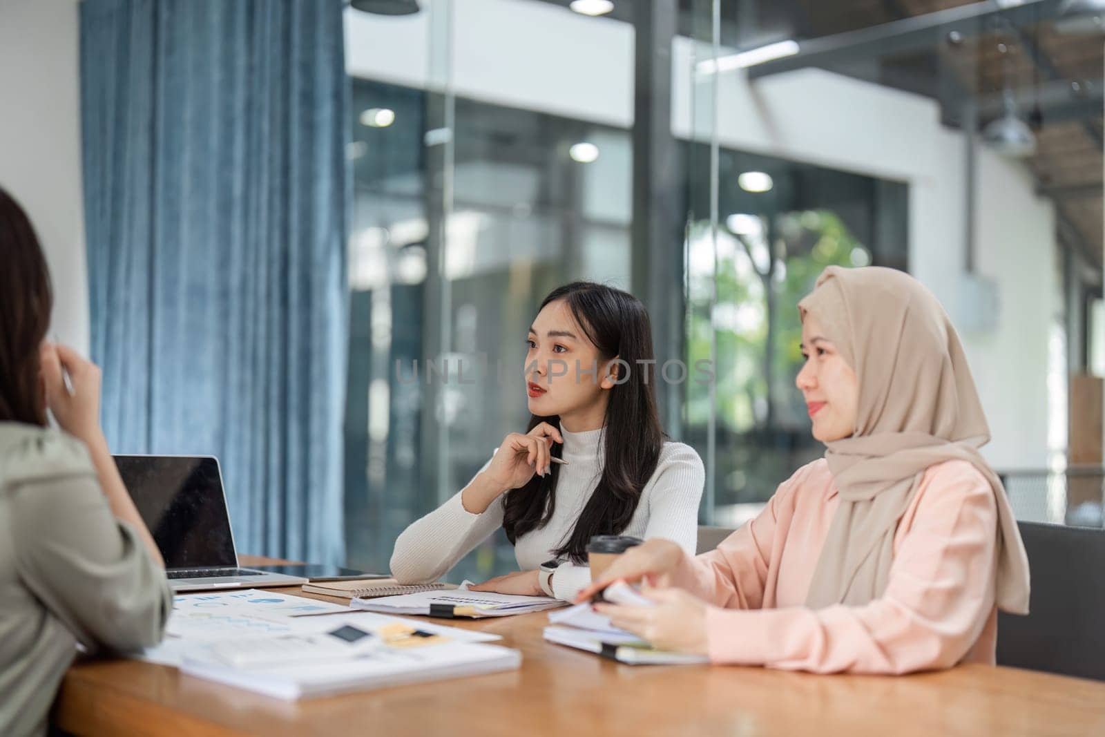 A diverse group of women engages in a strategic discussion during a meeting in a modern office.
